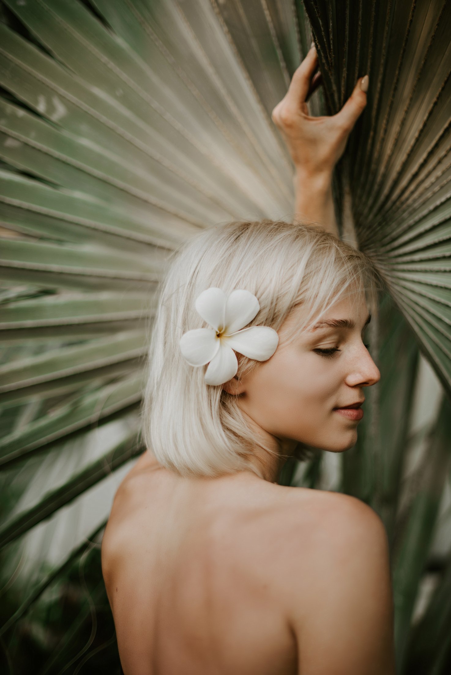 Woman With a Flower on Hair Near a Palm Leaf